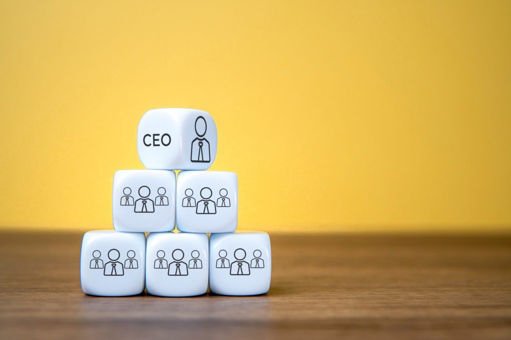 Pyramid of six white dice with people icons and text CEO. Copy space for text. Business hierarchy, leadership, and team structure concept.